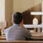 vista traseira jovem orando na igreja