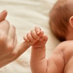 mae sem rosto com bebe nu crianca segurando o dedo da mamae mae passando um tempo com seu filho pequeno sobre fundo claro