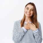 retrato de uma mulher loira sorridente de maos dadas no coracao olhando com expressao de gratidao expressar gratidao e alegria agradeco ajuda em branco 1